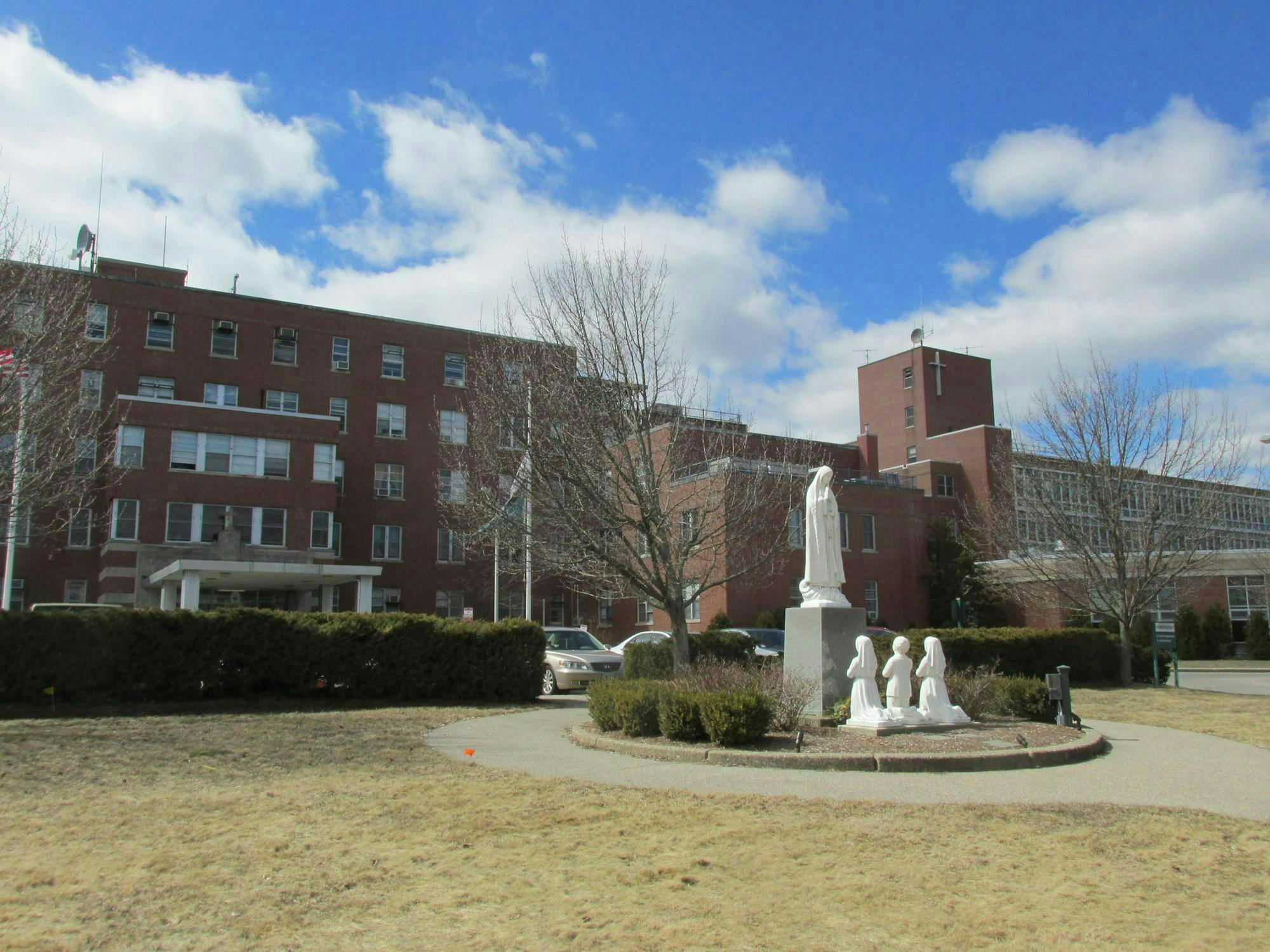 A photo of the front of Our Lady of Fatima during daytime, including the statue of three children praying in front of the Virgin Mary.