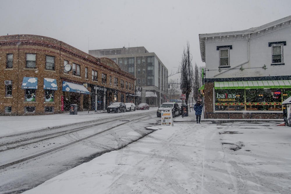 In this photo, a main street with multiple restaurants is covered in snow and mostly empty of people.