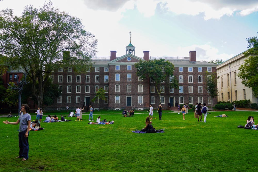 Photo of University Hall with students sitting and talking on the Main Green in front of it.