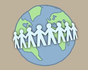 A string of paper cutout people loop around the front of a globe.