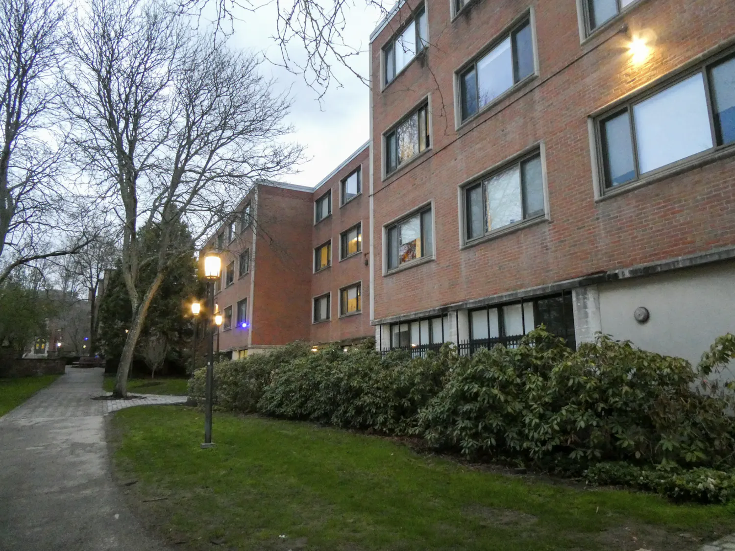 A brick and concrete brutalist building is surrounded by green grass on a rainy, grey day.
