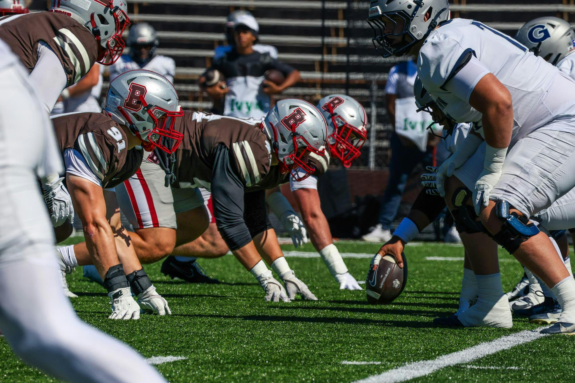 Photo of football players at the start of a play, a line of Brown University players staring down Georgetown's offense.
