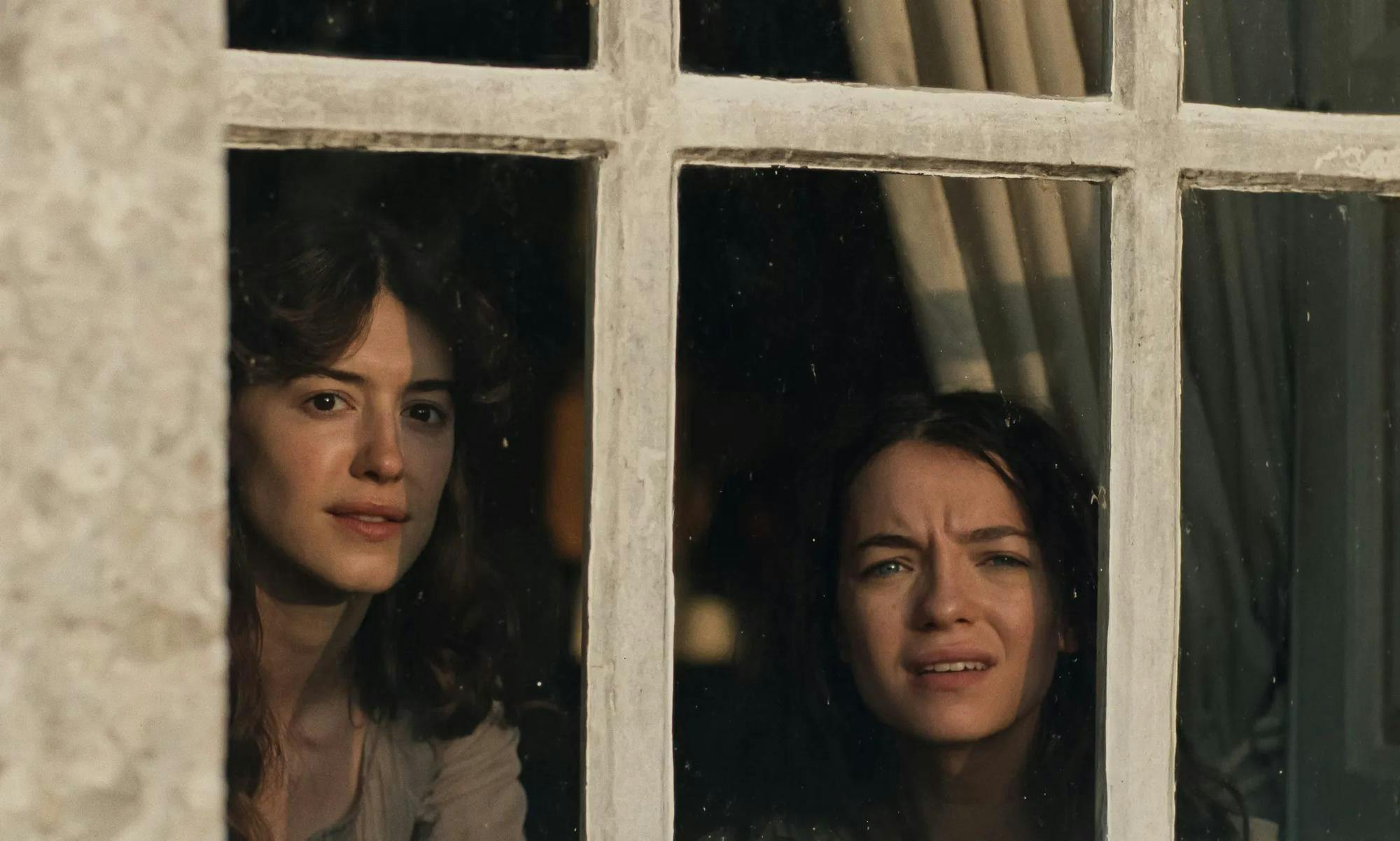 A scene from “Sense and Sensibility” showing actresses Daisy Edgar-Jones and Esmé Creed-Miles staring out of a window.