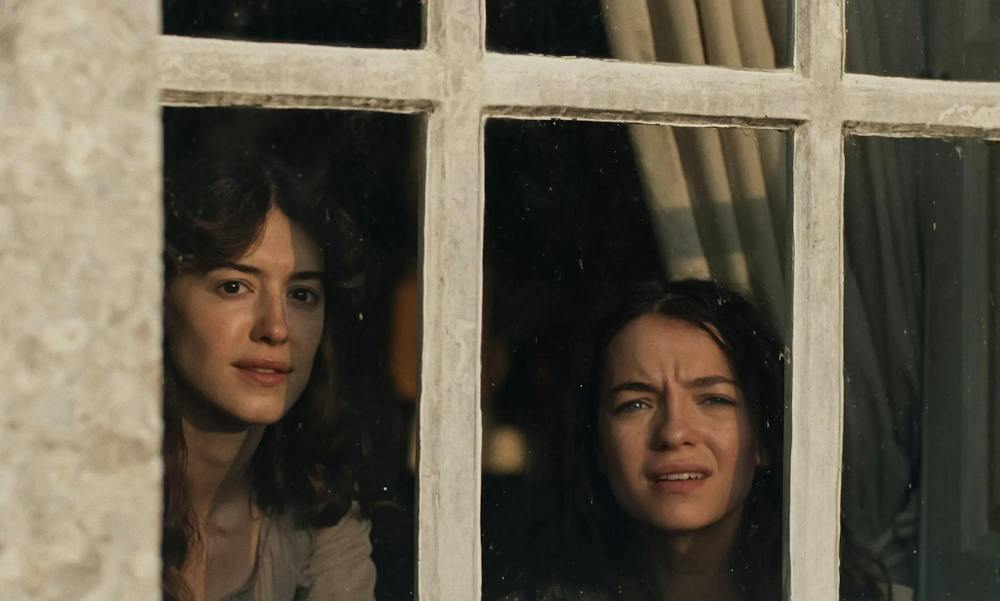 A scene from “Sense and Sensibility” showing actresses Daisy Edgar-Jones and Esmé Creed-Miles staring out of a window.