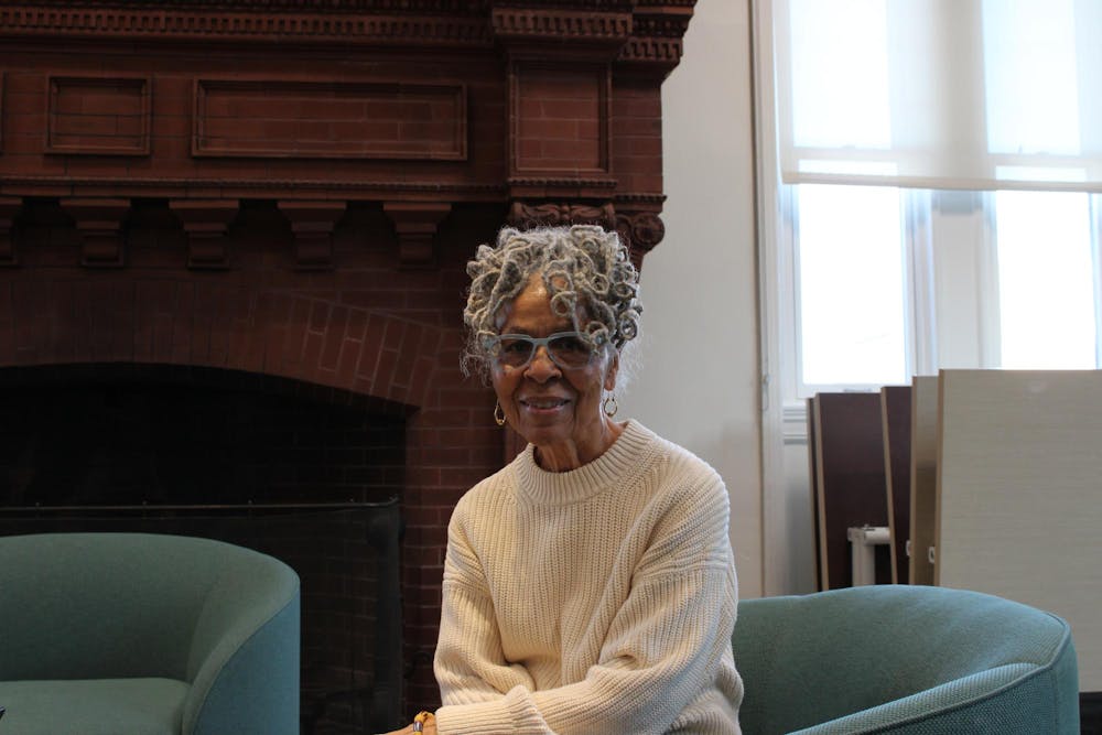A portrait of Mary Helen Washington. She has gray hair and is wearing a white knitted sweater and blue glasses.