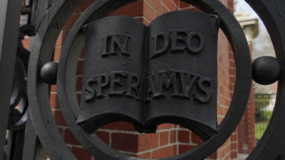 A picture of a metal detailing on the Van Wickle Gates at Brown University. The detailing features an open metal book, with the words In Deo Speramus, Brown's motto.
