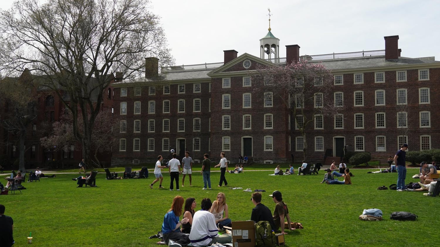 Students on the Main Green on a sunny day with University Hall in the background.