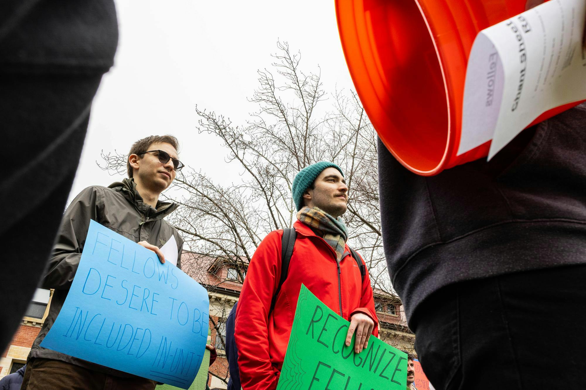 Two graduate fellow men hold protest signs. 