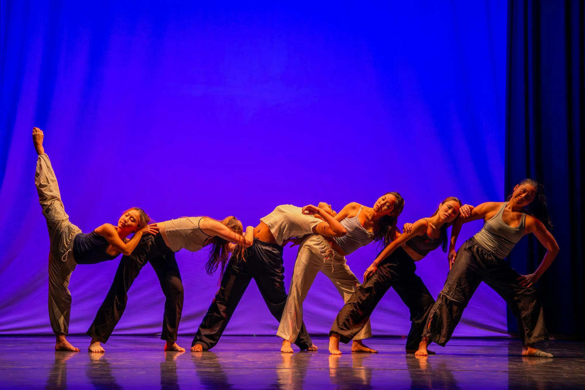 Photo of dancers leaning into each other in front of a blue background.