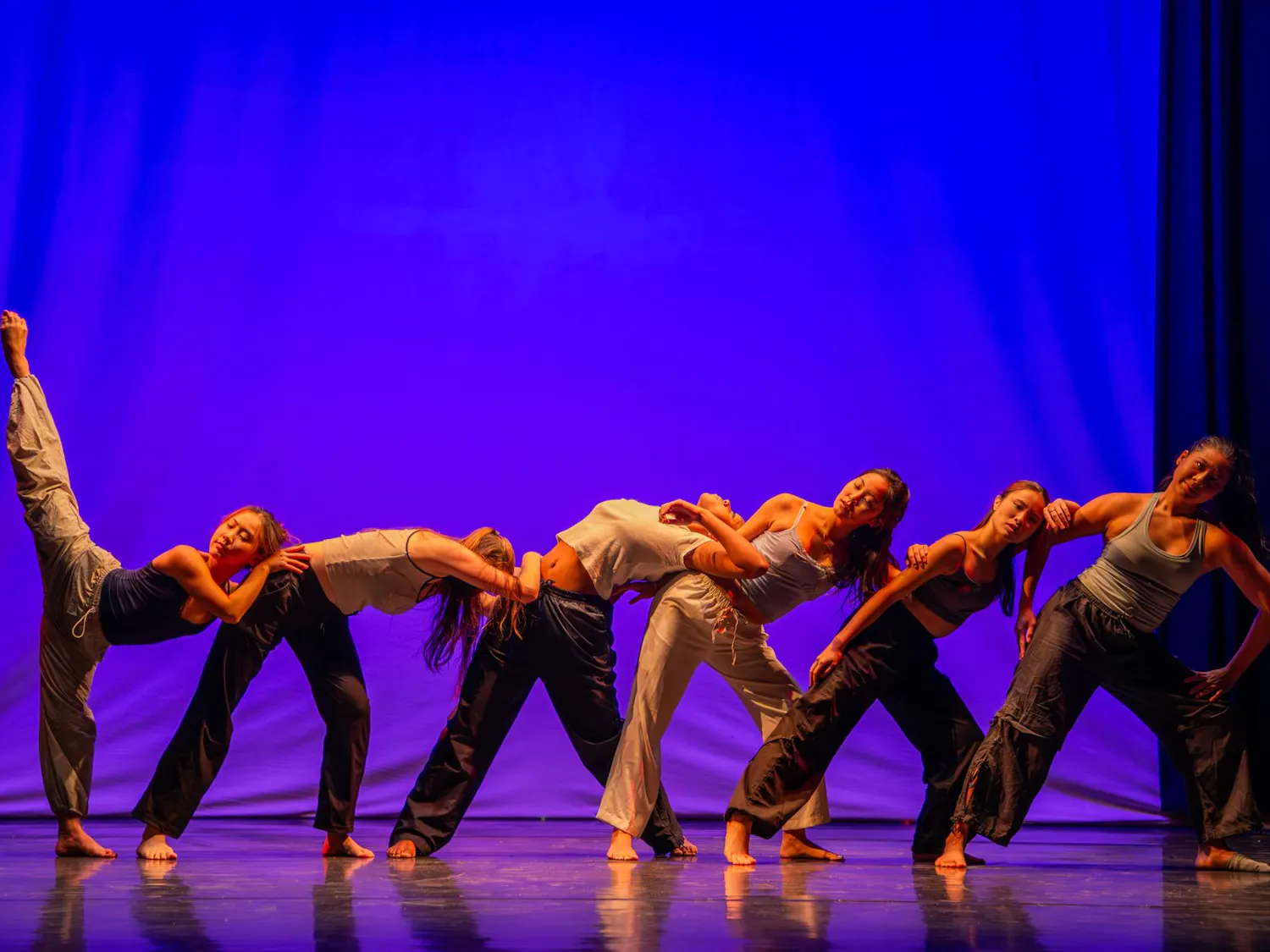 Photo of dancers leaning into each other in front of a blue background.