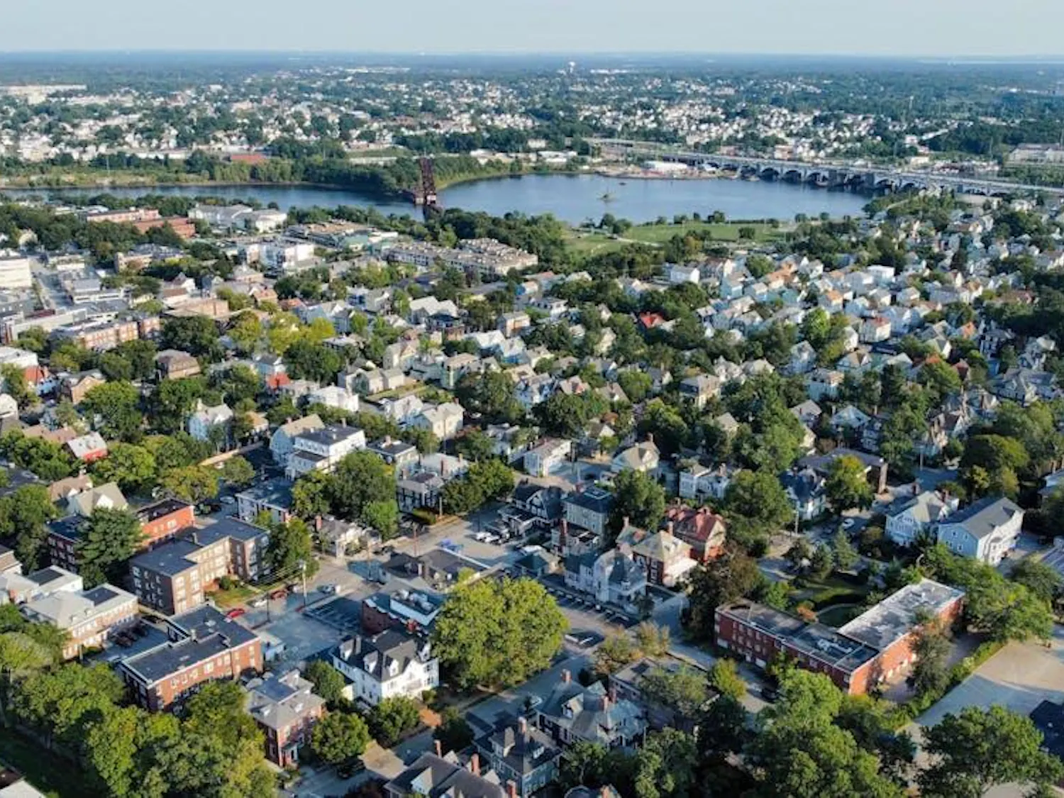 A bird's-eye view type photograph of Providence featuring houses, trees, and views of the river running through the city.
