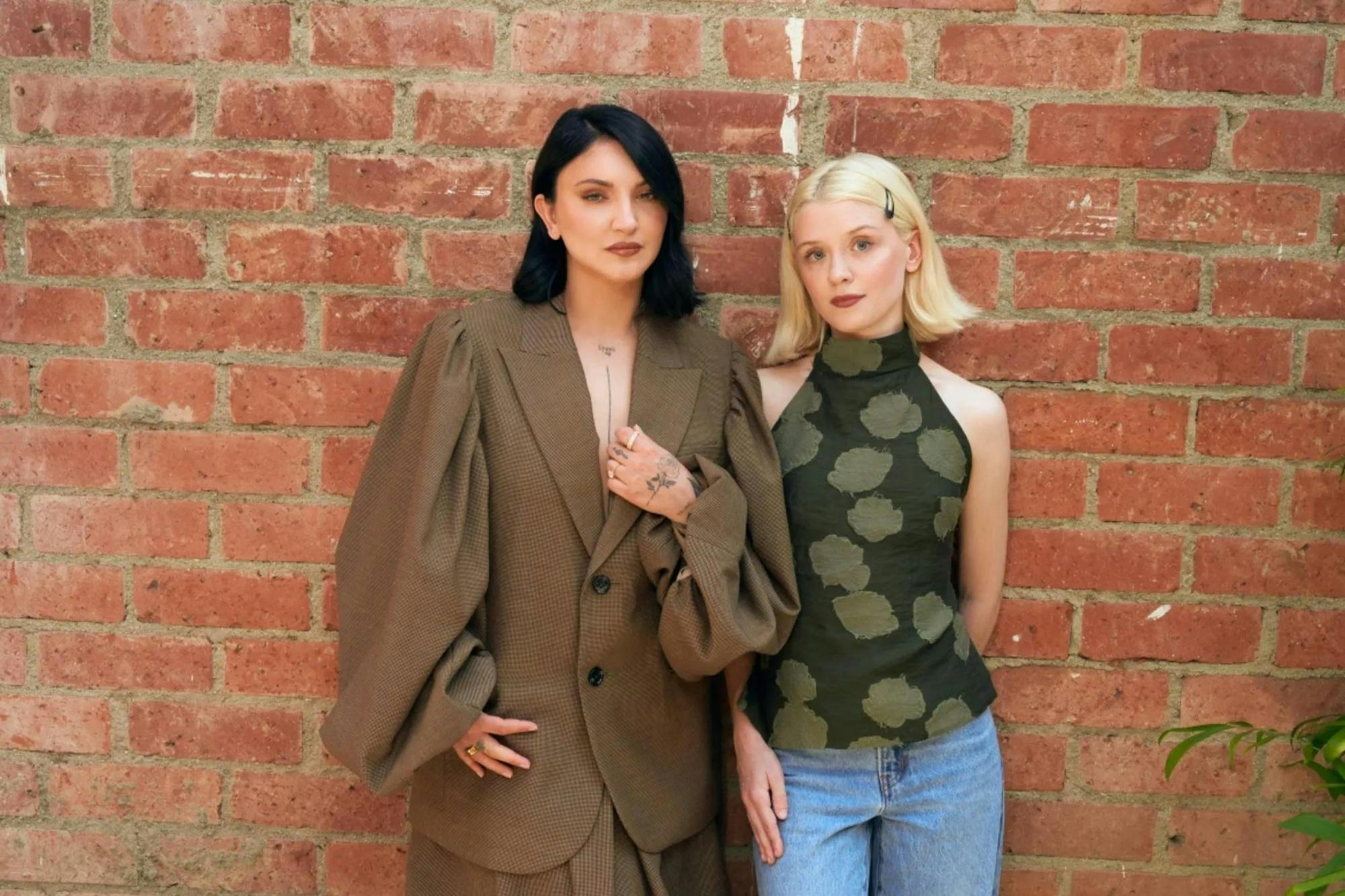 Photo of two women posing in fashionable attire.

