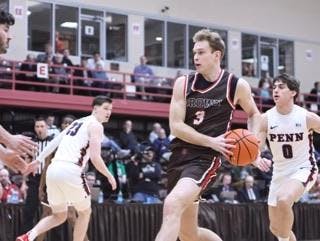 A man begins to shoot a basketball with his opponents behind him. 