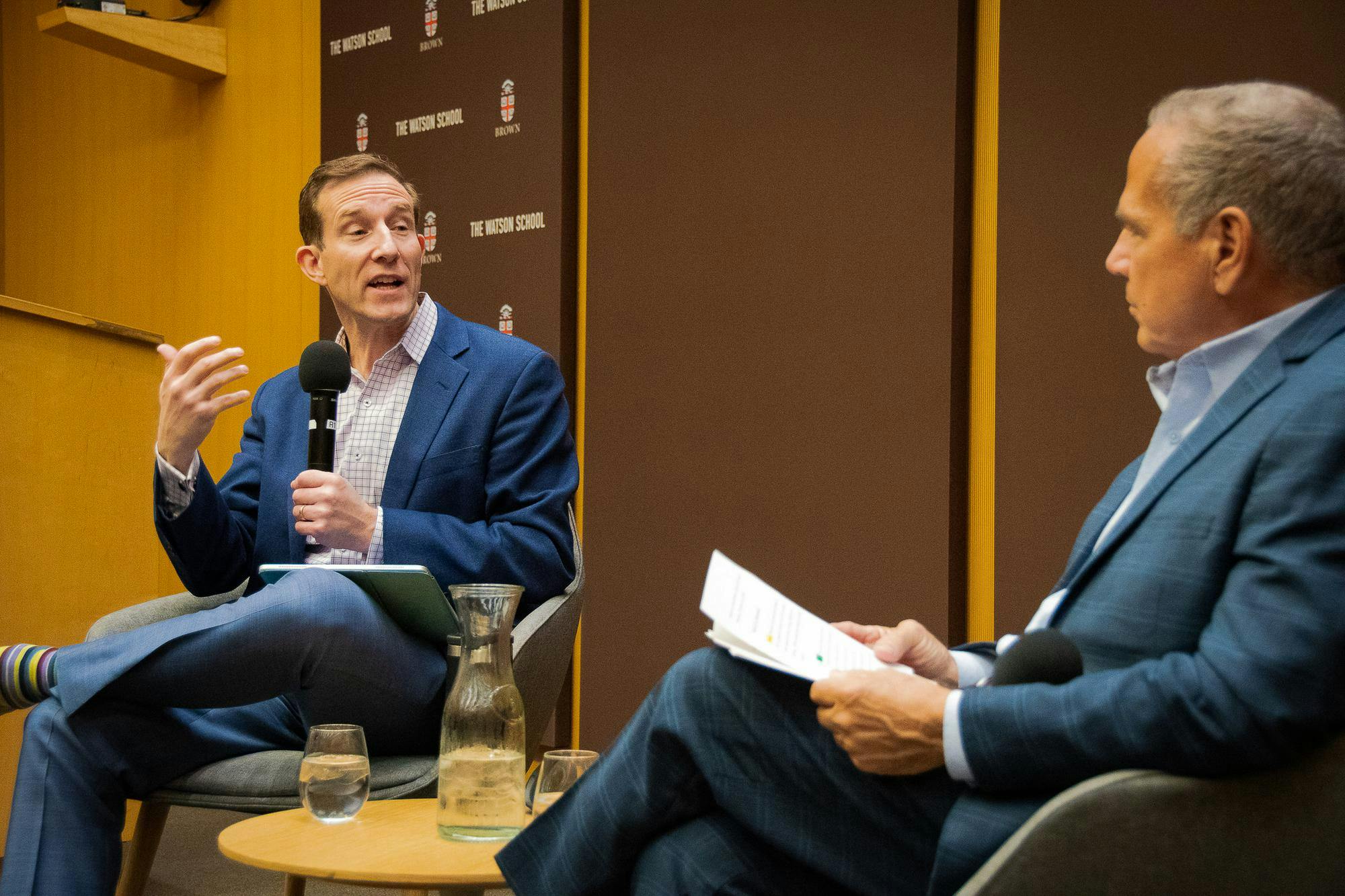 Photo of John Friedman, a professor of economics and international and public affairs and the dean of the Watson School of International and Public Affairs, speaking to someone during a lecture.