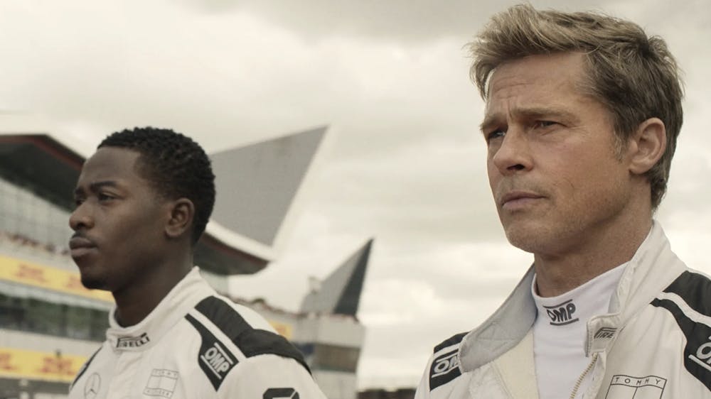 Still from “F1” showing Sonny Hayes (right), played by Brad Pitt, and Joshua Pearce (left), played by Damson Idris.