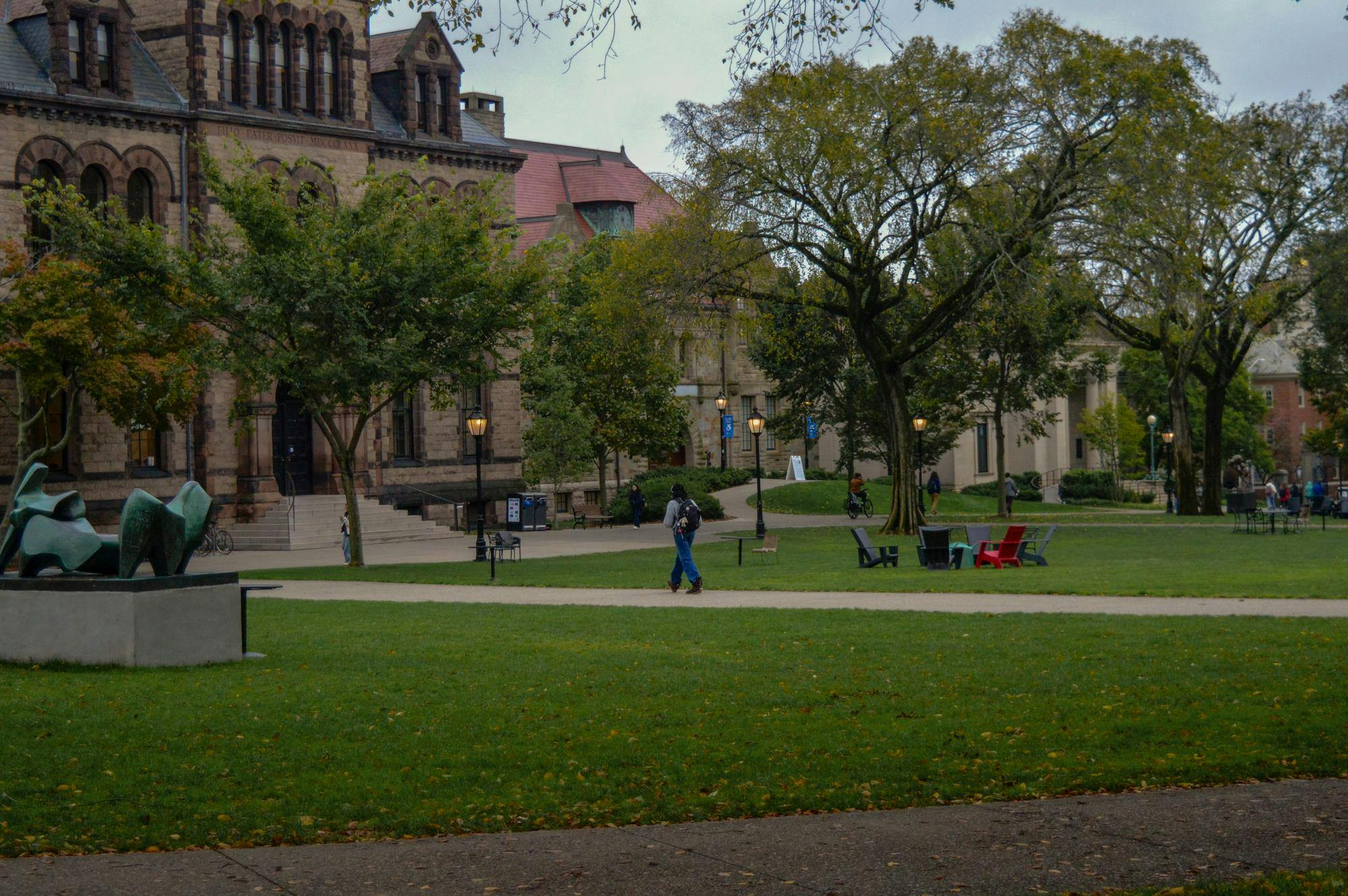 Photo of a student walking across the Main Green towards Sayles Hall.