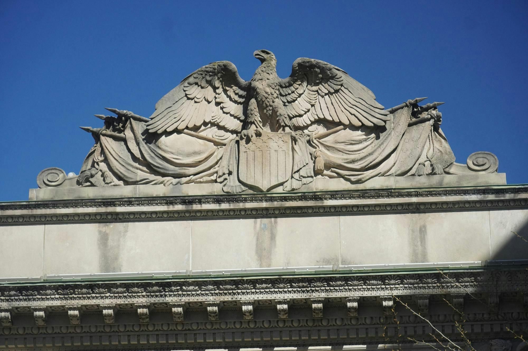 A concrete eagle in front of a blue sky.