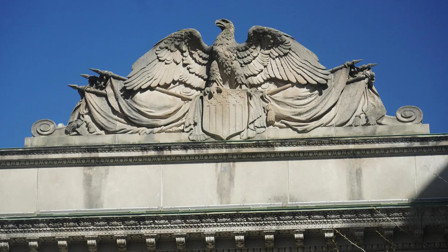 A concrete eagle in front of a blue sky.