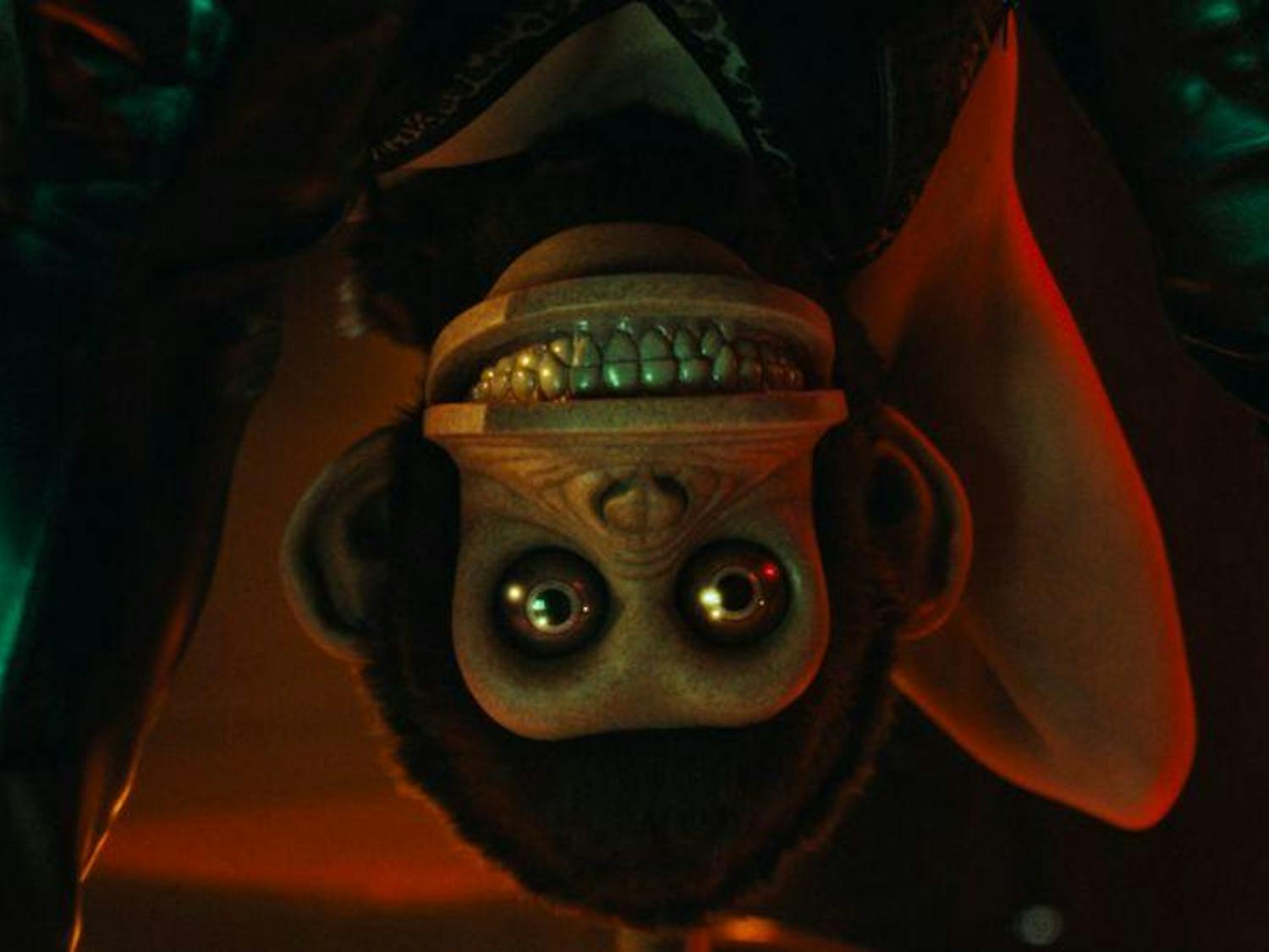 The head of a stuffed monkey on a person's body, staring at the camera through their legs.