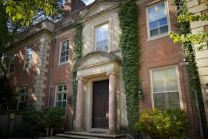 Photo of a brick building with vines growing upon both sides of the front door. 
