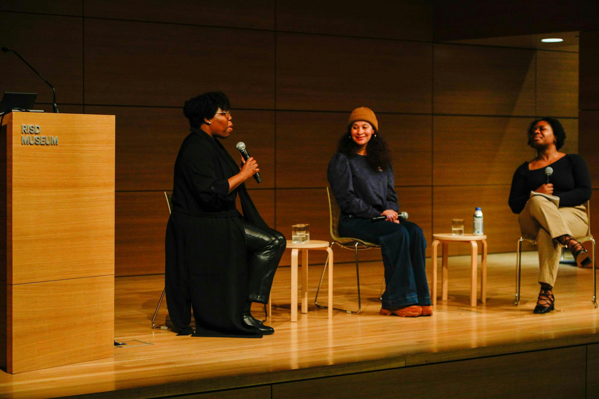 A picture of panelists Jeneé Osterheldt and Charlotte Abotsi and moderator Tyanna Buie at the screening of "Out of the Picture" at the RISD Metcalf Auditorium.