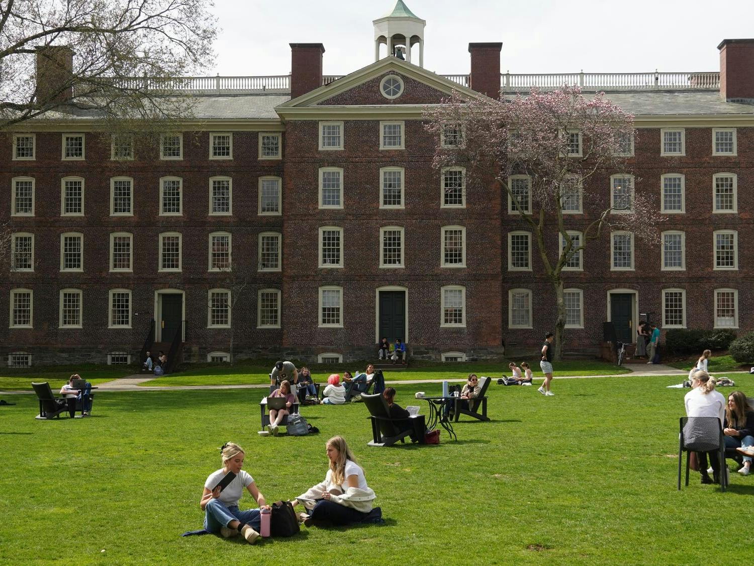 Students on the green in front of University Hall on a sunny day.