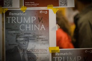 The image focuses on a poster advertising the panel, and features Donald Trump's face as well as the words "Rematch: Trump v China." The edges of a few other taped-up posters are also visible. 