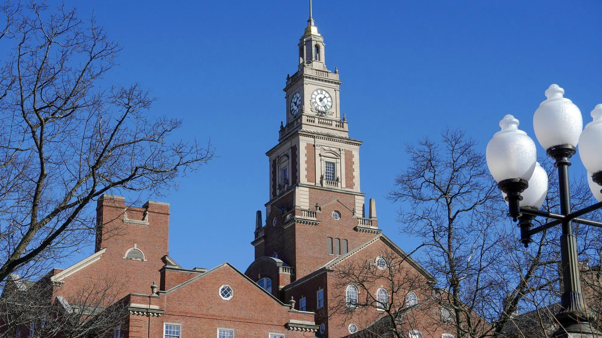 A picture of a brown building with a clock near the top.