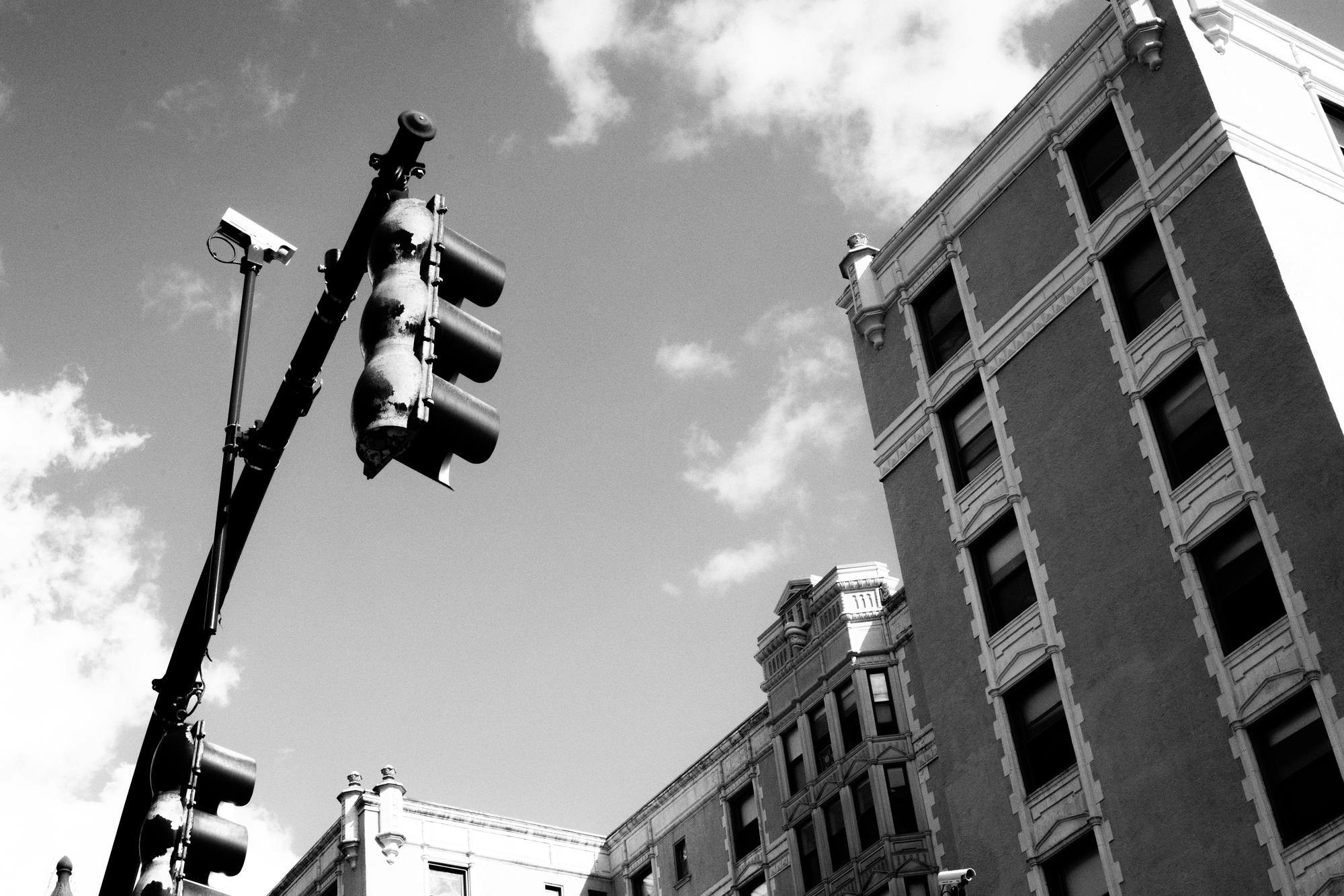 Black and white photo of a brick apartment building and stop light.


