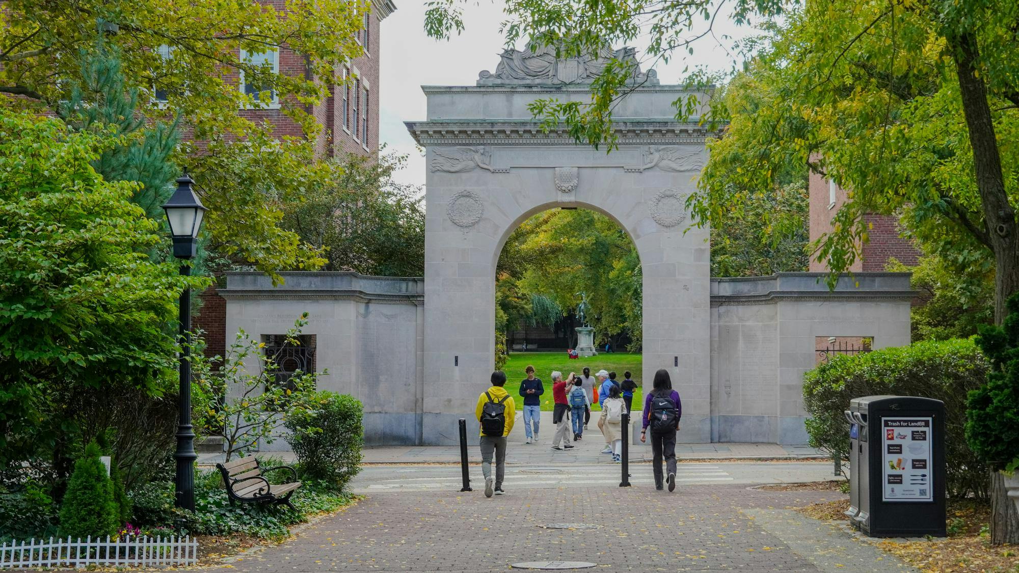 Students walk through the Soldiers Memorial Gate, which is surrounded by trees.