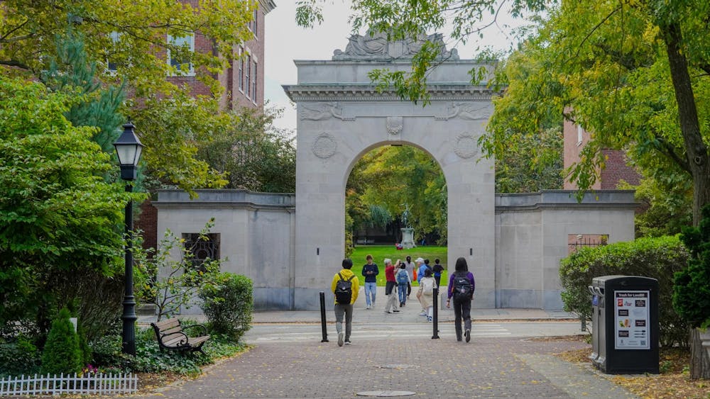 Students walk through the Soldiers Memorial Gate, which is surrounded by trees.