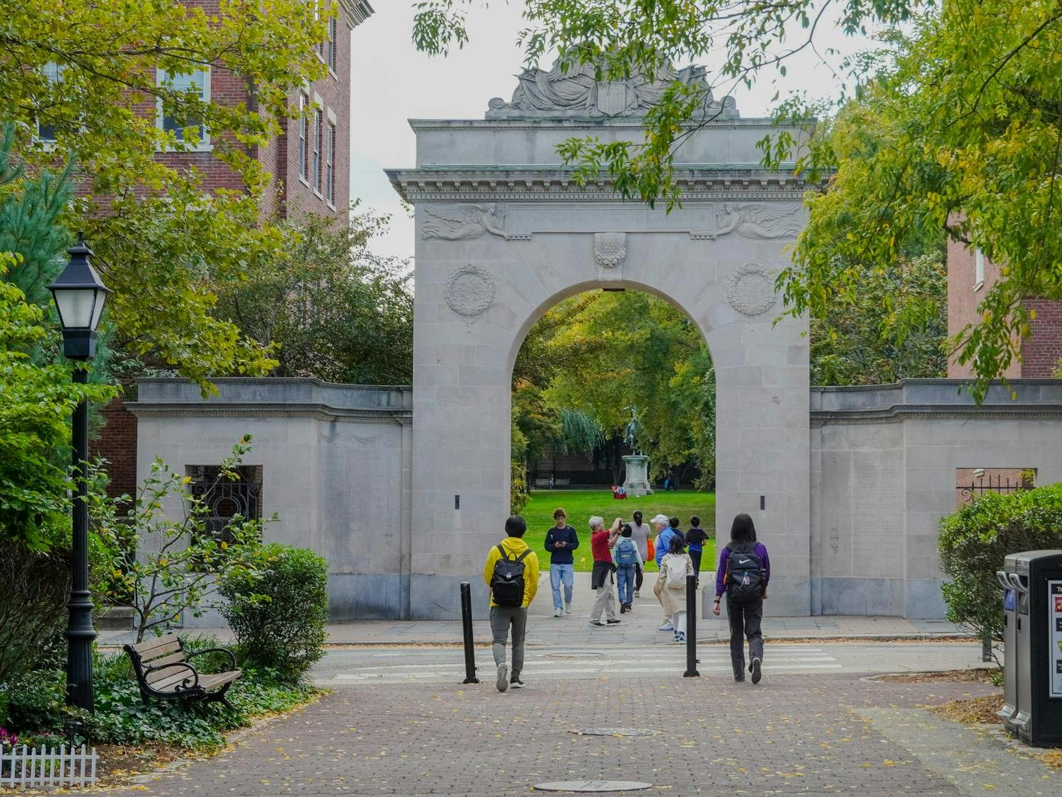 Students walk through the Soldiers Memorial Gate, which is surrounded by trees.