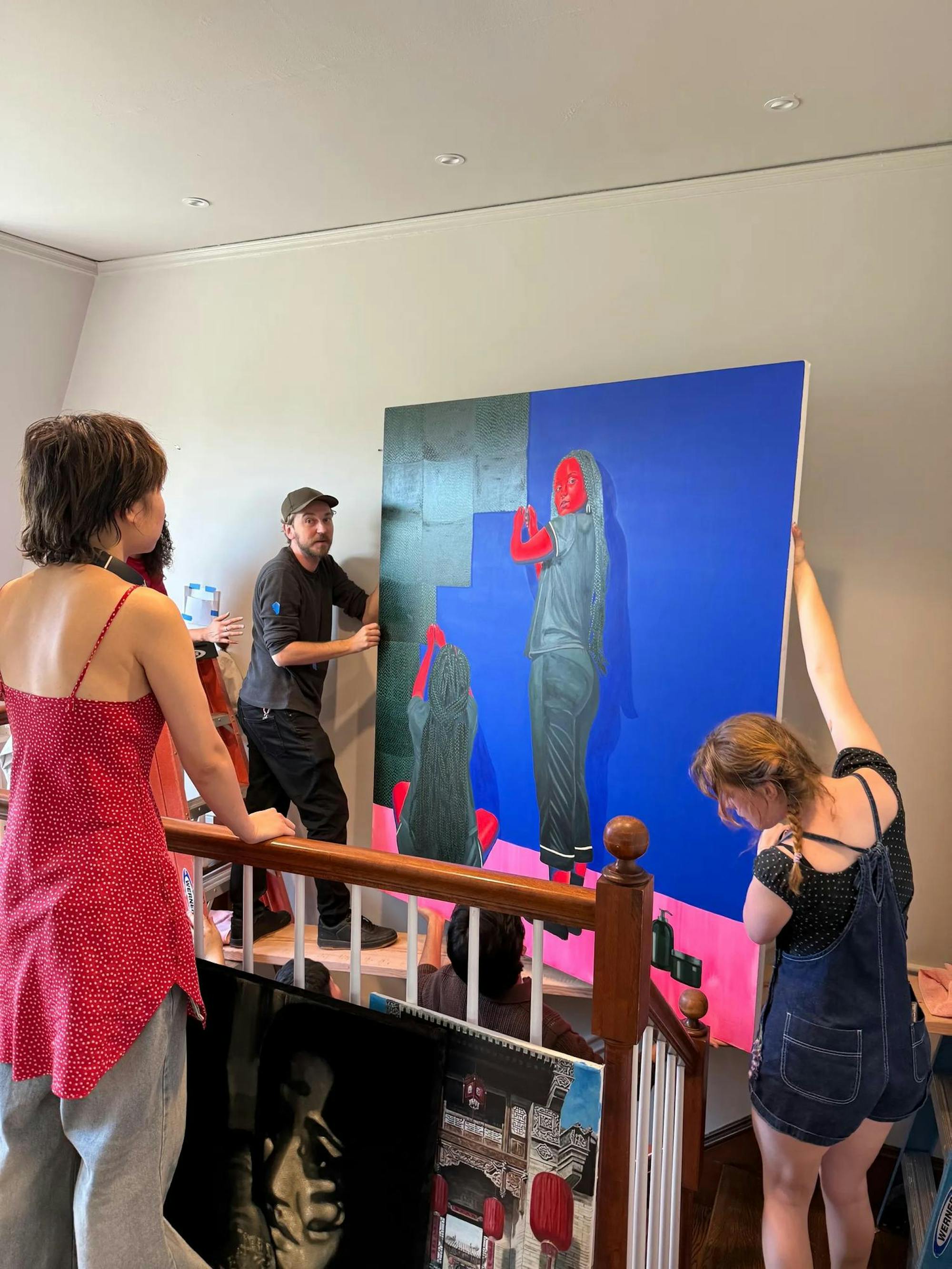 Photo of students installing a painting for display during the exhibition.
