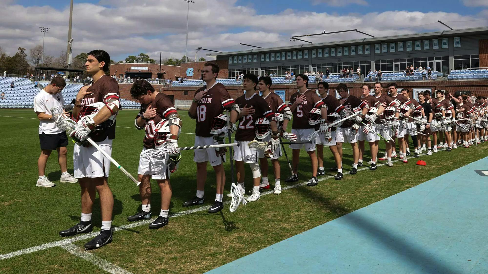 The Brown Men’s Lacrosse team stands with their right hands on their chest for the Pledge of Allegiance.