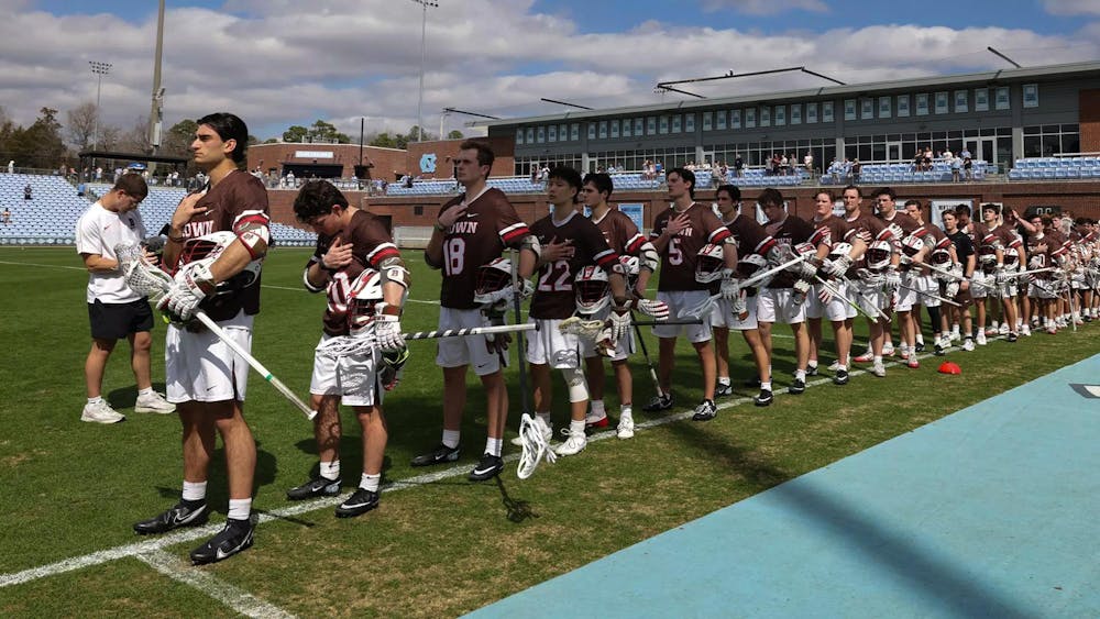 The Brown Men’s Lacrosse team stands with their right hands on their chest for the Pledge of Allegiance.