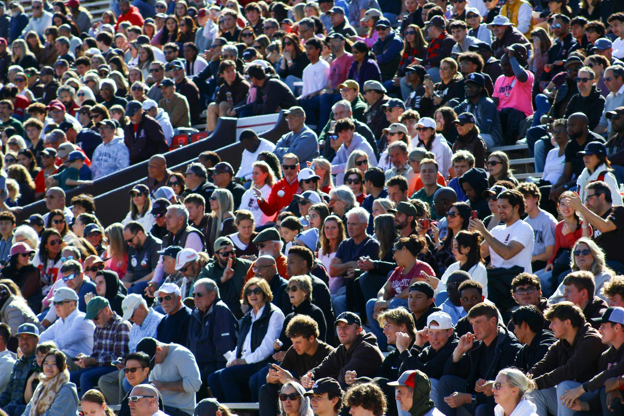 Photo of a crowd sitting in elevated stands at a football game.