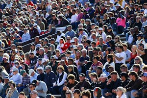 Photo of a crowd sitting in elevated stands at a football game.