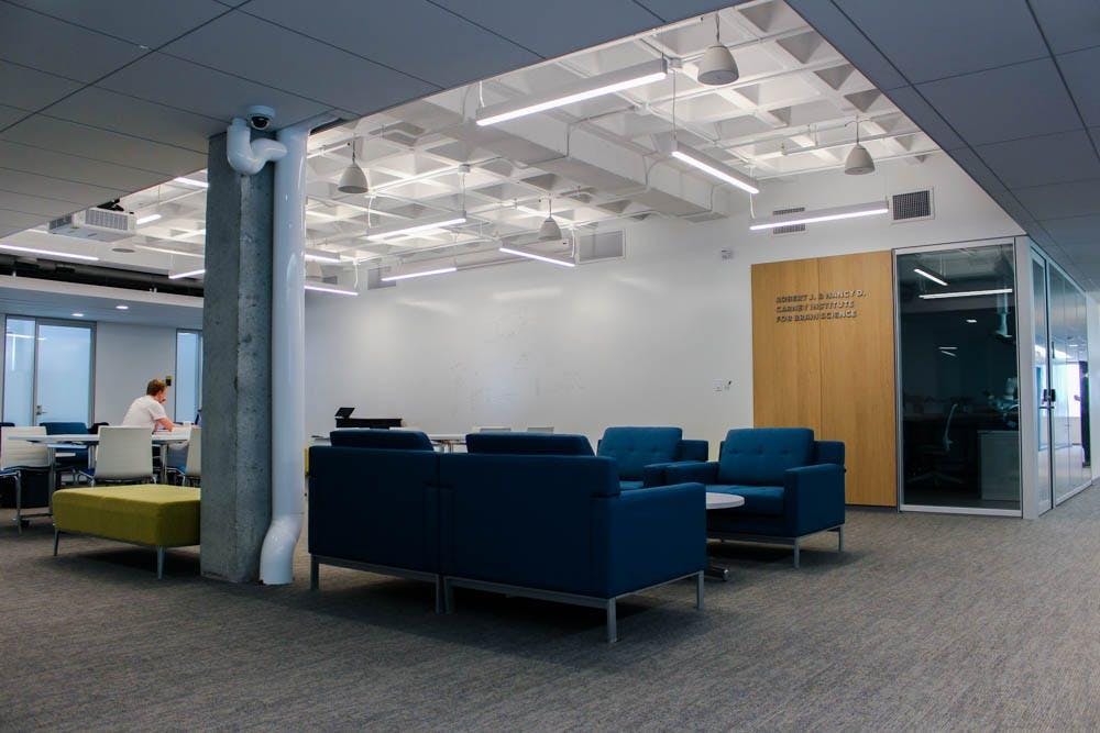 Photo of the Carney Brain Institute offices with navy blue couches, a grey wall and exposed concrete.