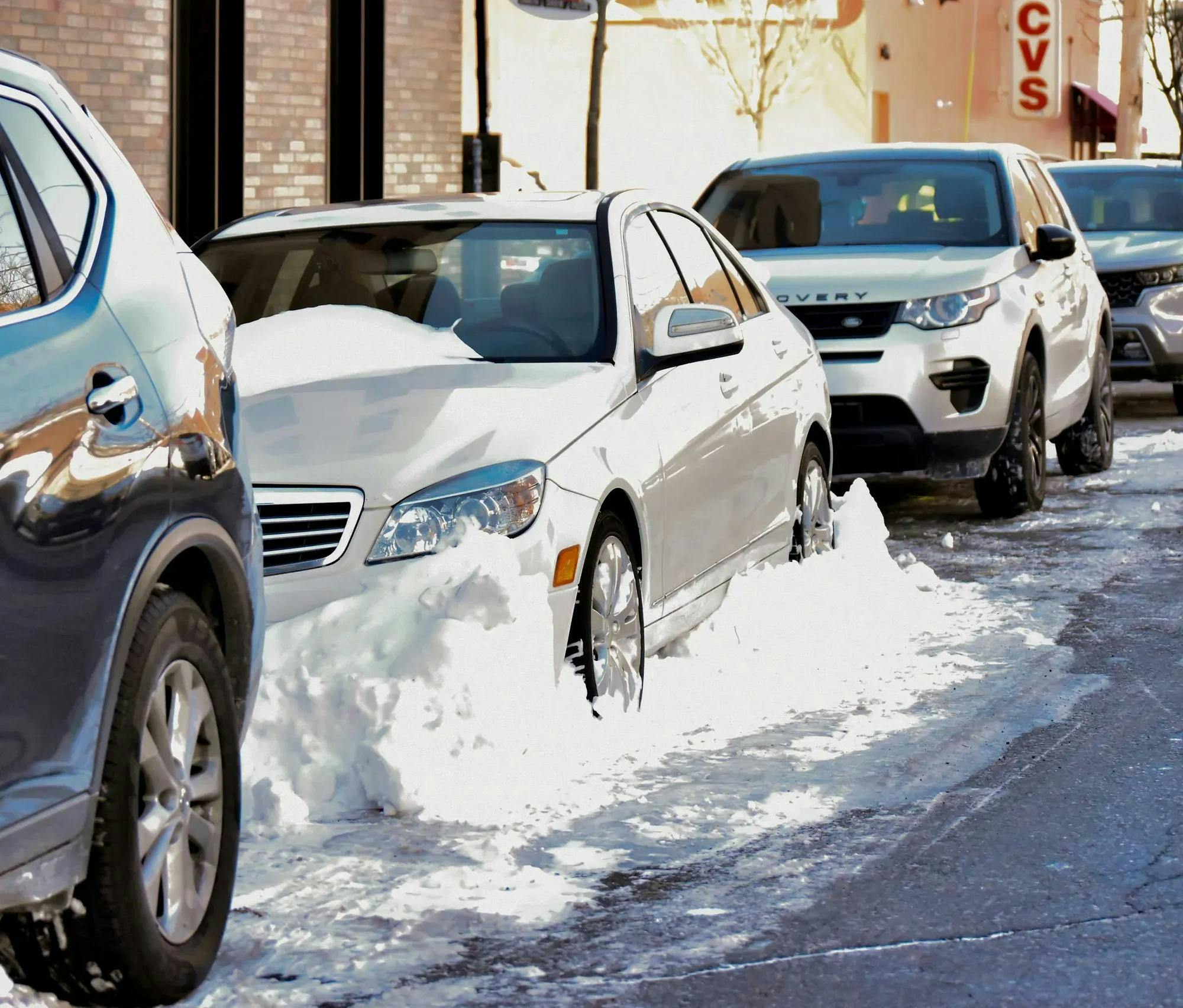 Pictured on Cushing St., a white sedan is walled in by snow. 