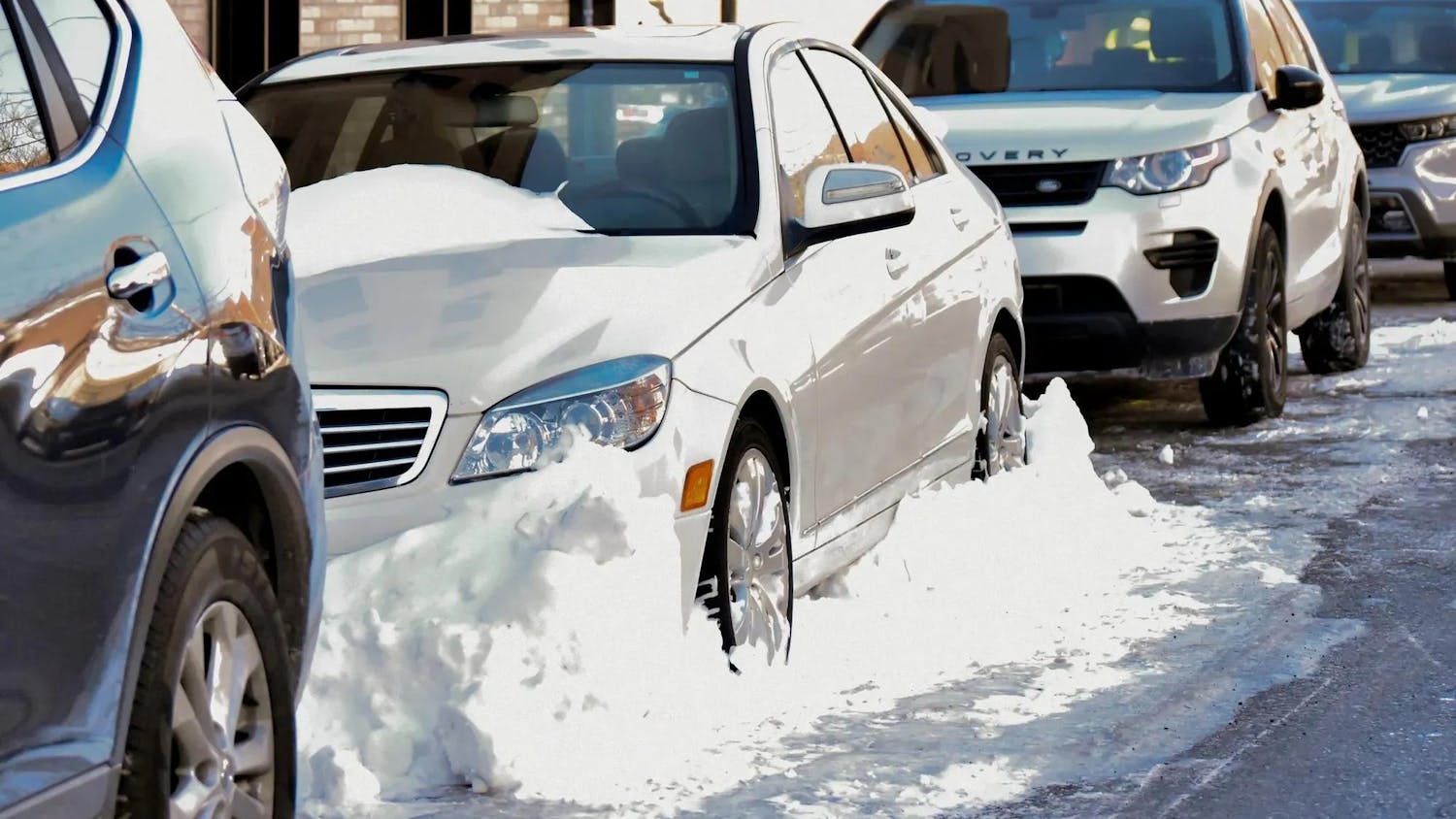 Pictured on Cushing St., a white sedan is walled in by snow.