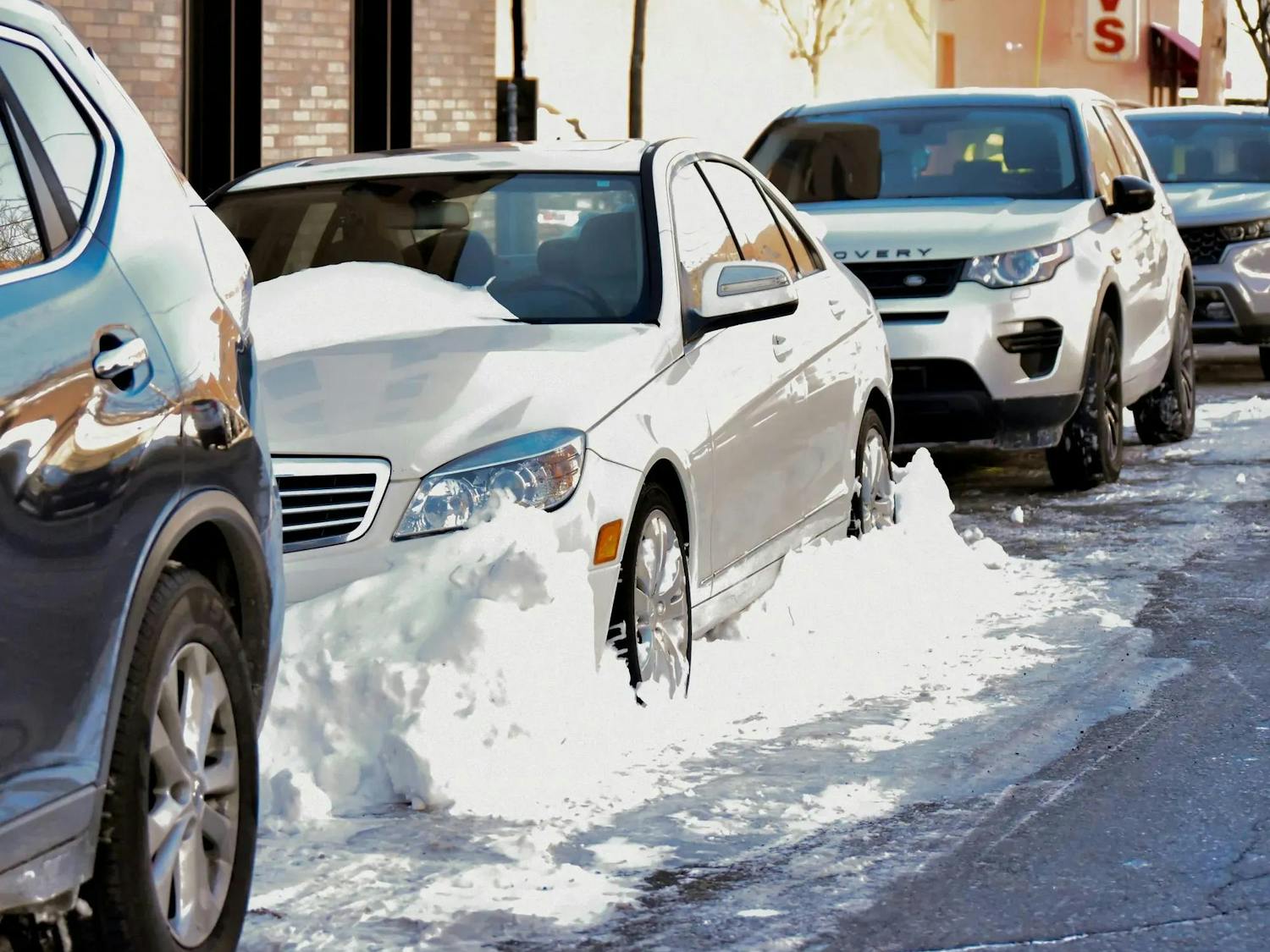 Pictured on Cushing St., a white sedan is walled in by snow.