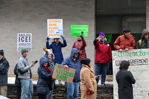 A photo of group of protestors outside of Citizens Bank hold up various signs that read “BOYCOTT CITIZENS BANK,” “CITIZEN BANK FUNDS ICE PRISONS,” “CITIZENS BANK IS COMPLICIT WITH ICE,” and “ABOLISH ICE.”