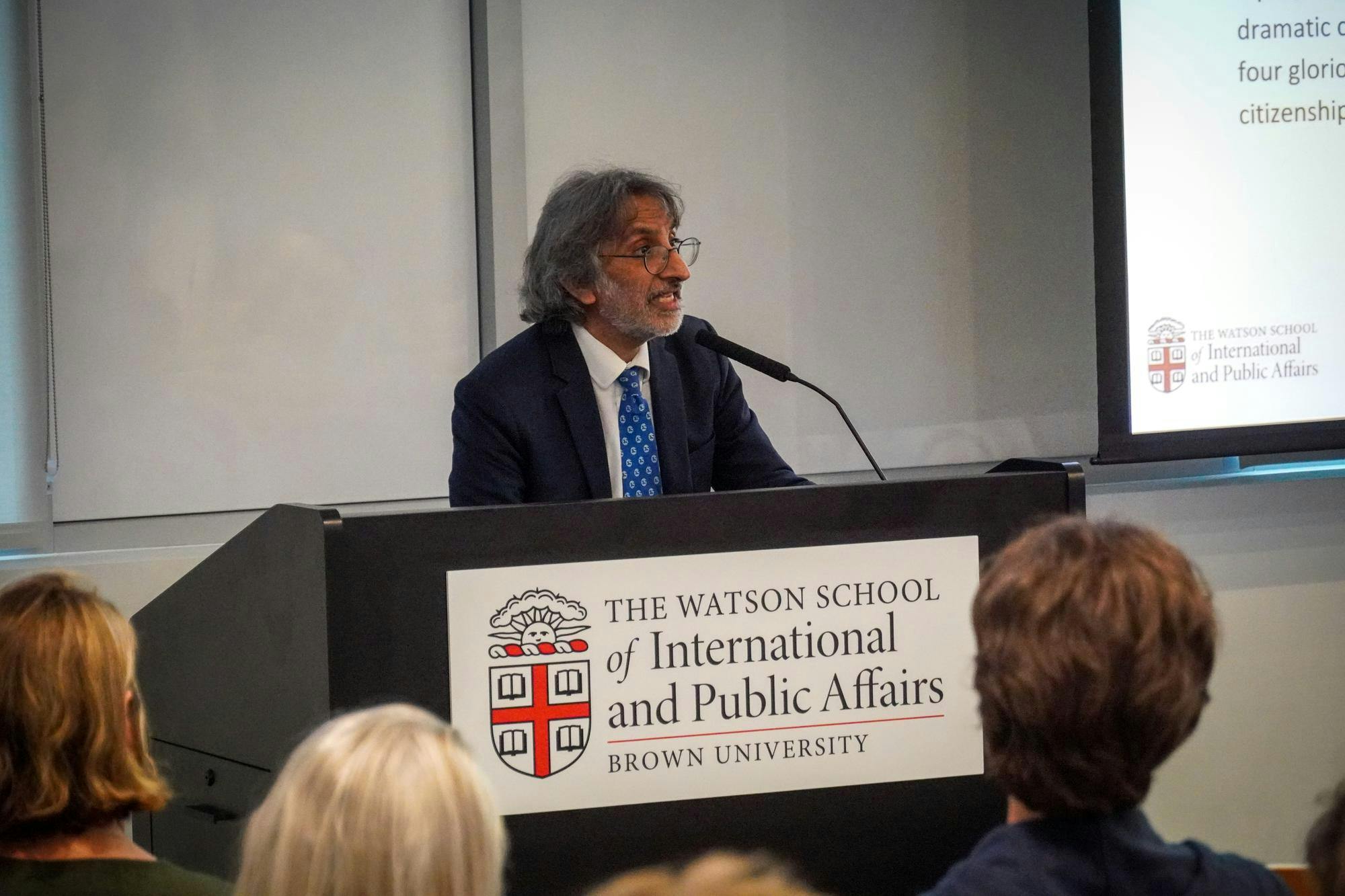 Photo of a man in a suit giving a speech at a podium.