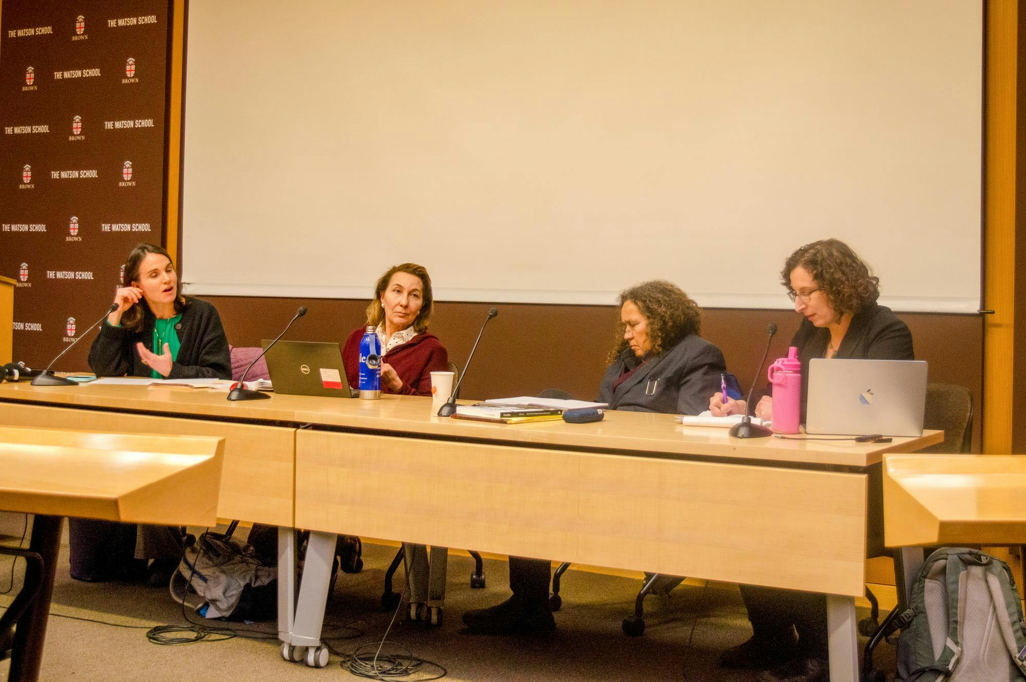 Photo of four professors sitting at a long table in a line during a panel.