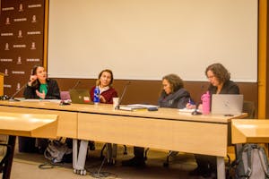 Photo of four professors sitting at a long table in a line during a panel.