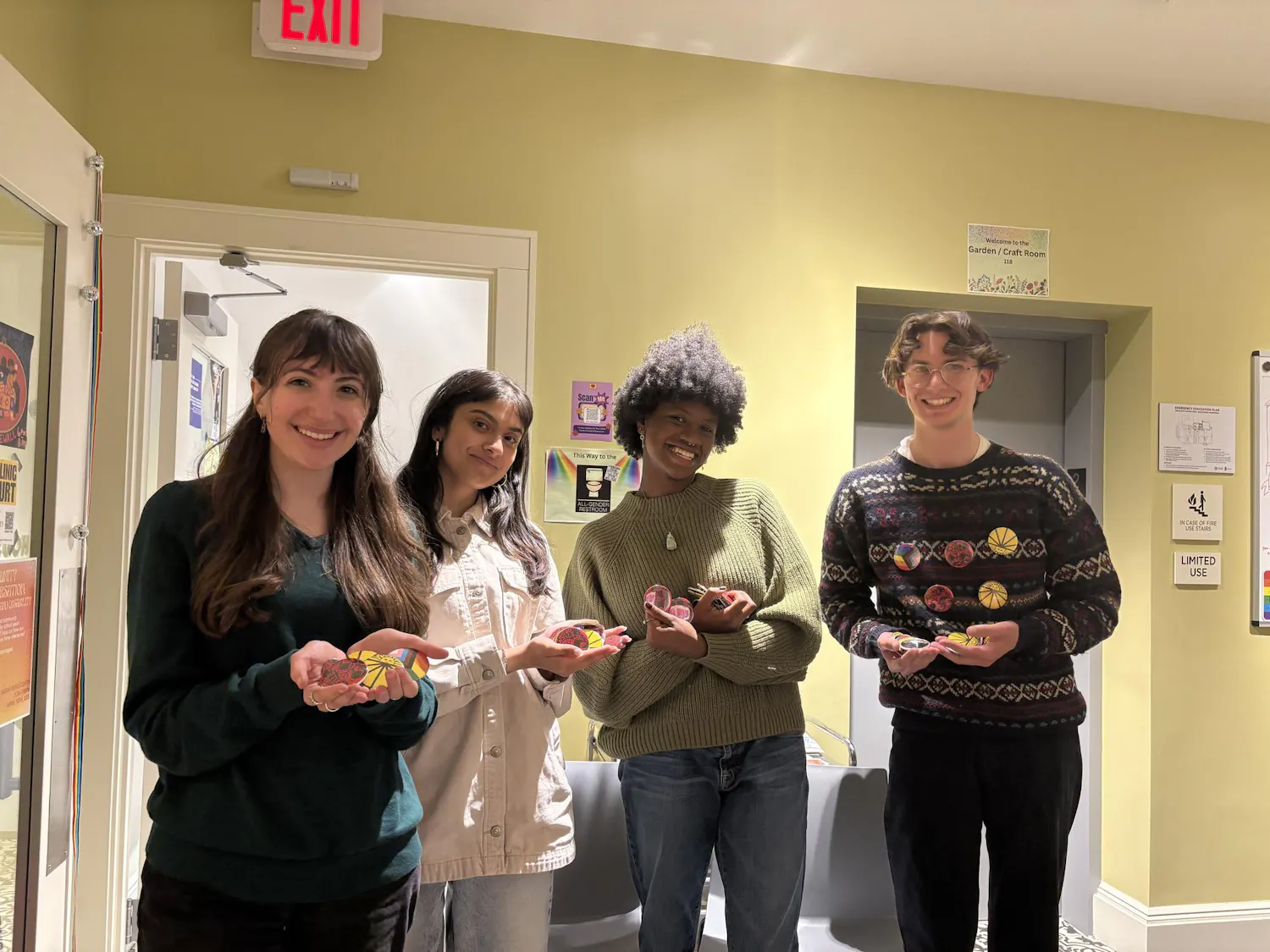 Four students stand and hold various pins relating to Earth Day.