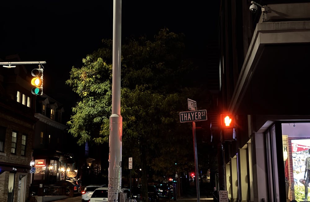 A photo of the intersection between Thayer street and Angell street at night.