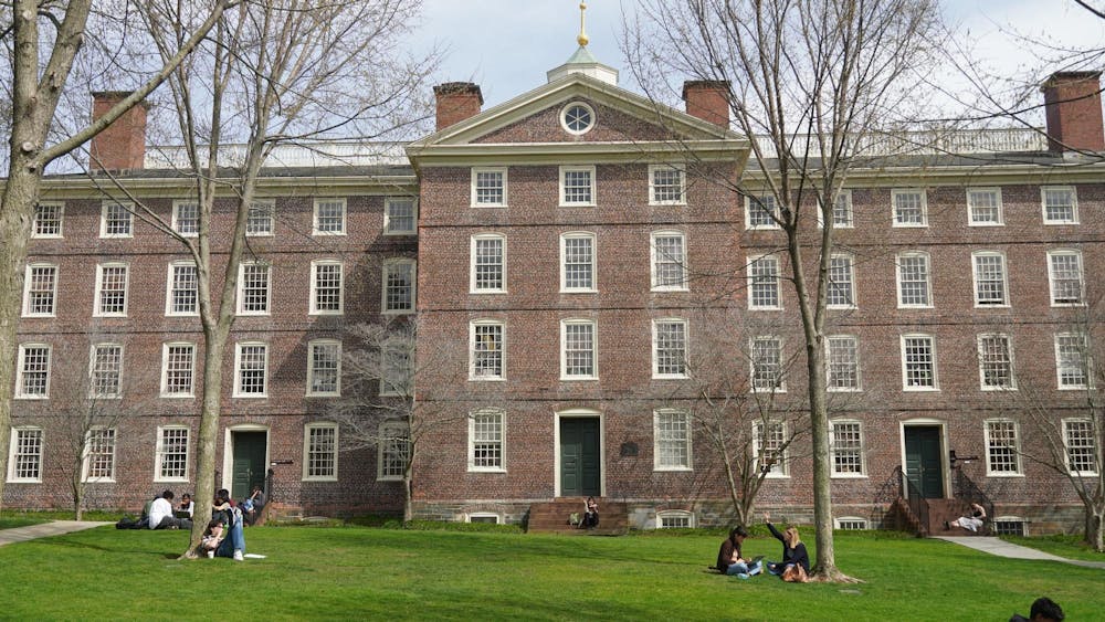 A picture of Brown University's University Hall, with several students sitting in front of the building.