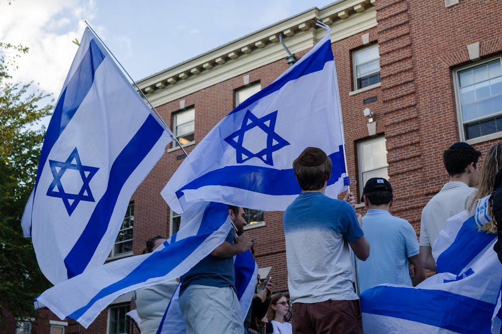 Photo of students from behind of holding Israeli flags with other students beside them.