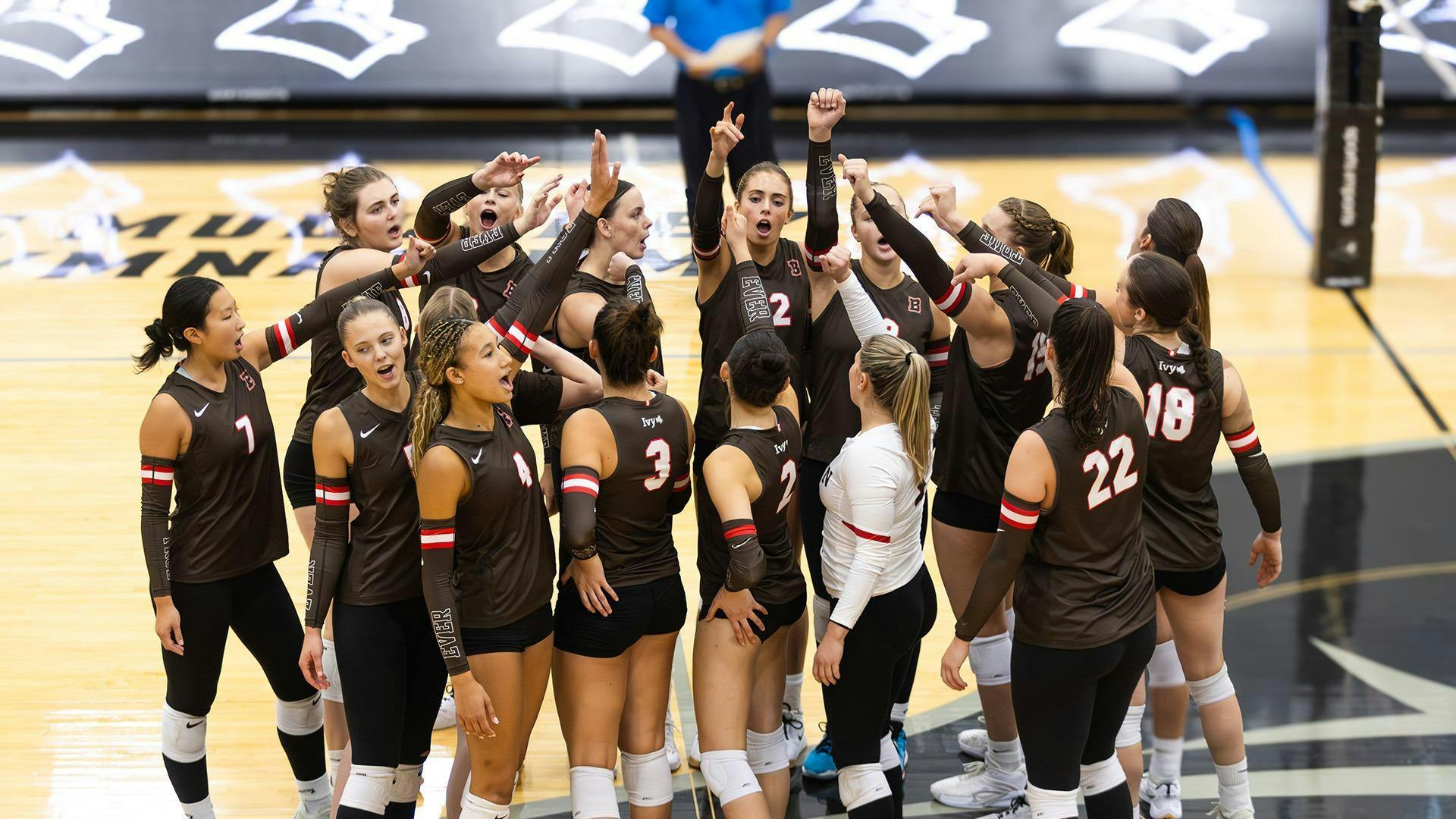 Photo of the women’s volleyball team breaking after a team huddle.